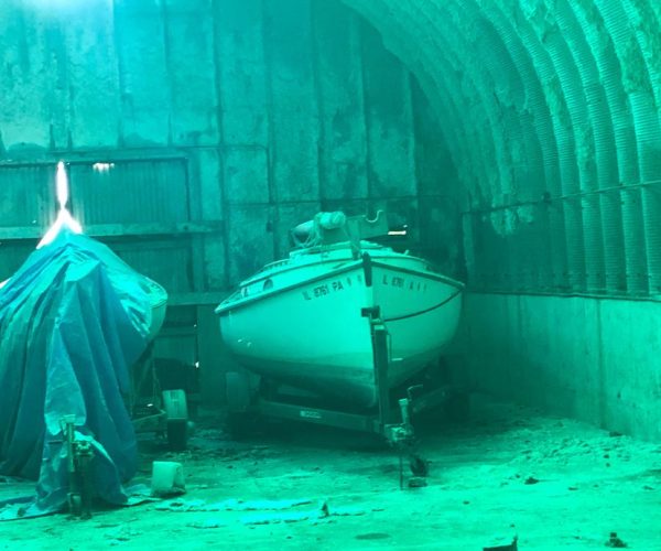 A boat covered with a tarp inside a garage.